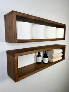 two wooden shelves with white towels and bottles on them, one shelf is holding several rolls of toilet paper