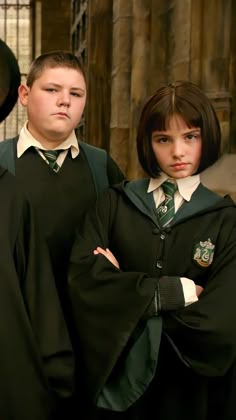 two children dressed in harry potter robes posing for the camera with their hands on their hipss