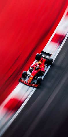 a red race car driving on a track with motion blurry around the front wheel