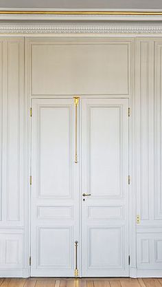 an empty room with white walls and wooden flooring is pictured in this image, there are two doors that lead into the closet