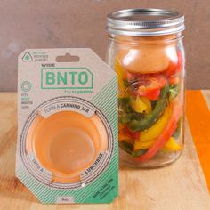 a glass jar filled with sliced vegetables next to a container of brown liquid on top of a wooden table