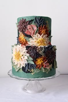 a multi - tiered cake decorated with flowers and leaves