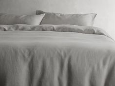 an unmade bed with white sheets and pillows