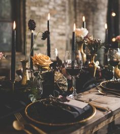 a table set with candles, plates and flowers