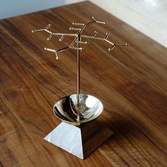 a metal cup on a wooden table with four branches sticking out of the top and one branch in the middle