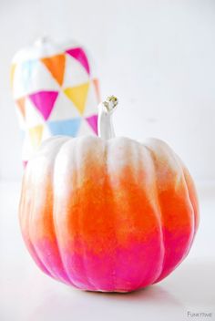 a white and orange pumpkin sitting on top of a table next to a colorful vase