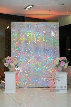 a large display with flowers and vases on pedestals in front of a wall