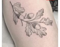 a tattoo with leaves and acorns on the thigh is shown in black and white