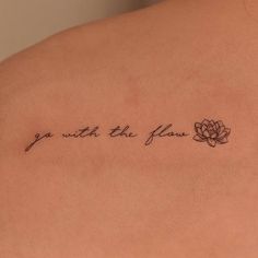 a woman's back with a tattoo saying go with the flow