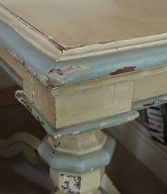 an old wooden table with peeling paint on it's top and bottom edges, sitting in a living room