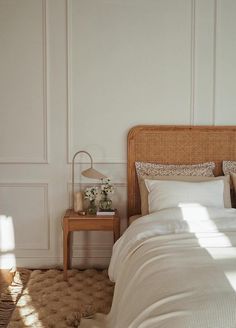 a bed with white sheets and pillows next to a wooden night stand in a bedroom