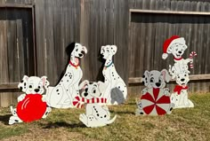 three dalmatian dogs with candy canes in front of a fenced in yard