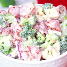 broccoli and cauliflower salad in a white bowl on a red table