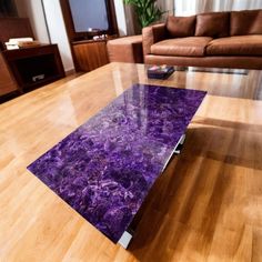 a glass table with purple marble on top in a living room area next to a couch