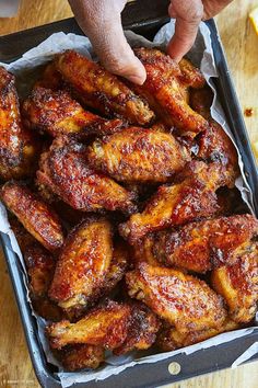 a tray filled with chicken wings on top of a wooden table