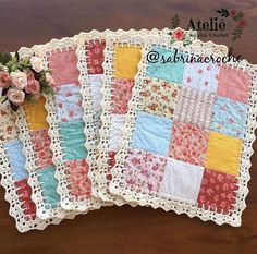 three quilts with flowers on them sitting on a wooden table next to each other