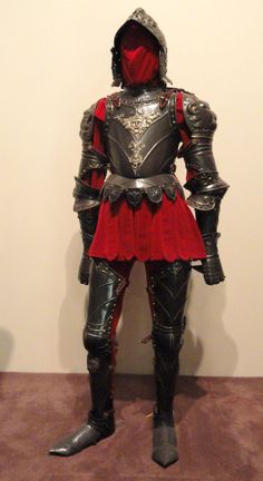 a man dressed in armor standing next to a wall