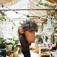 a woman holding a large potted plant in her hands