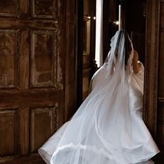 a woman in a white wedding dress is standing by a door