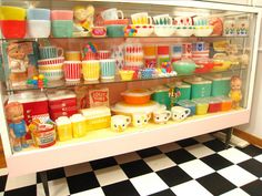 a display case filled with lots of cups and saucers on top of a black and white checkered floor