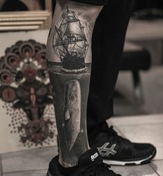 a man's leg with an elephant and ship tattoo on it