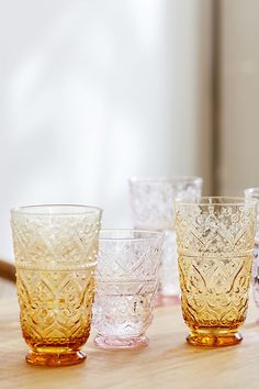 four glass cups sitting on top of a wooden table