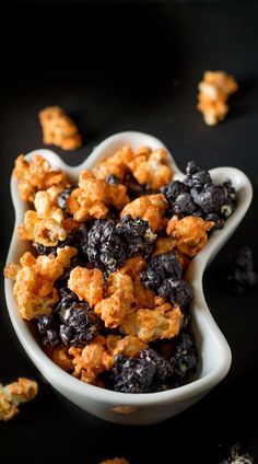 a bowl filled with blueberries and cereal on top of a black tablecloth next to other food items