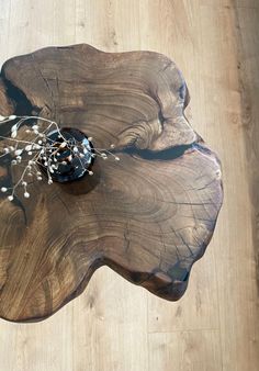 a wooden table topped with a vase filled with flowers on top of a hard wood floor