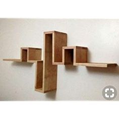 a cross made out of wooden blocks hanging on a white wall with no one around it