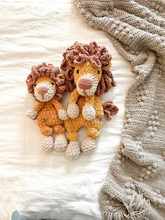 two crocheted stuffed animals laying on top of a bed next to a blanket