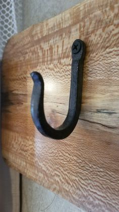 an iron hook is mounted on a wooden board