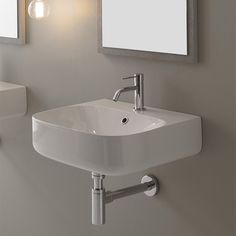 a bathroom sink sitting under a mirror next to a wall mounted soap dispenser