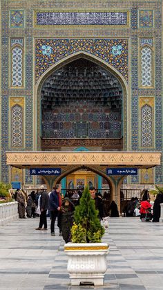 people are standing in front of an ornate building with blue and gold tiles on it