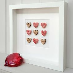 a white frame with wooden hearts and a red mouse