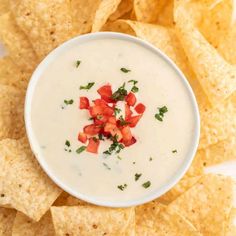 a white bowl filled with dip surrounded by tortilla chips