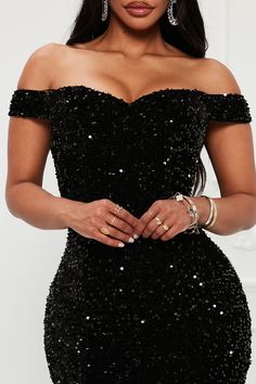 a woman wearing a black sequin dress with her hands on her hips and one hand in her pocket