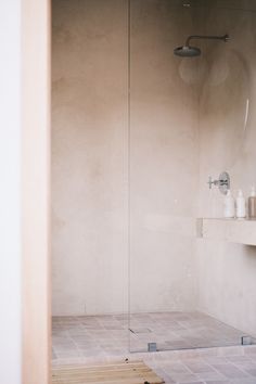 a bathroom with a walk in shower next to a sink and toiletries on the counter