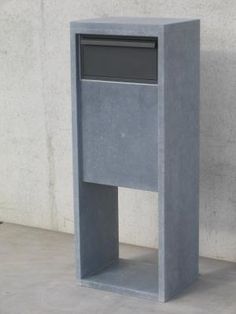 a concrete pedestal with a mailbox on the top and bottom, in front of a cement wall