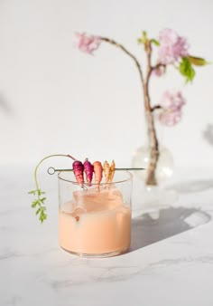 a small glass filled with food on top of a white table next to a vase