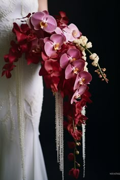 a woman holding a bouquet of flowers in her hand and wearing a wedding dress with beading