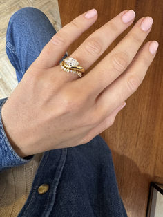 a woman's hand with a ring on top of her left hand and a wooden table in the background