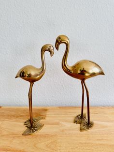 two brass flamingos standing next to each other