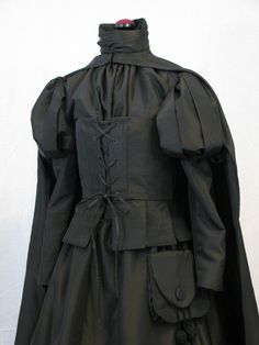 a woman's black dress with ruffles on the collar and sleeves,