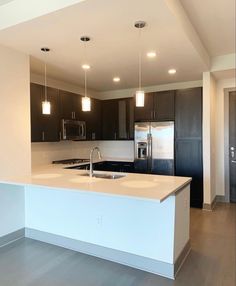 an empty kitchen with stainless steel appliances and dark wood cabinets