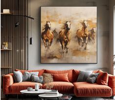 a living room with an orange couch and three horses on the wall in front of it