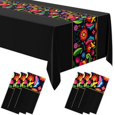 the table cloth is decorated with colorful flowers and paisley designs on black fabric, along with matching place mats