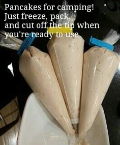 three pieces of food wrapped in plastic sitting on a white plate with blue and yellow handles