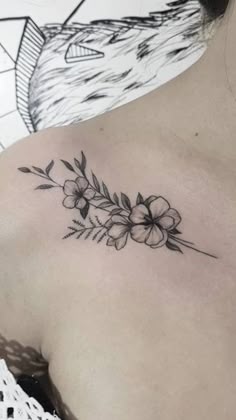 a woman's shoulder with flowers and leaves tattoo on her left side ribcage