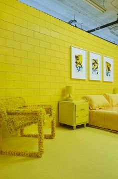 a living room with yellow walls and furniture in the corner, along with pictures on the wall