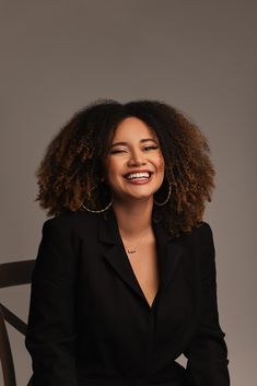 a woman sitting in a chair smiling at the camera